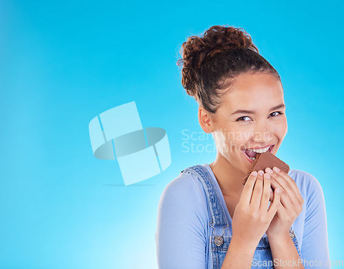 Image of Chocolate, diet and space with portrait of woman in studio for fast food, dessert and nutrition. Happy, cacao and sugar with person eating on blue background for candy, health and hungry mockup