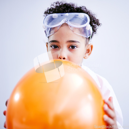 Image of Portrait, science and a kid blowing a balloon in studio on a gray background for a childhood experiment. Children, education and laboratory with a female child wearing goggles while learning