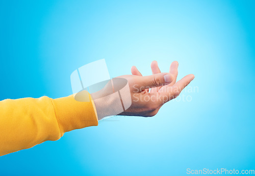 Image of Hands, giving and man in studio for charity, donation or help with reaching gesture against blue background. Palm, asking and male person with emoji for poverty, humanity and compassion, aid or hope