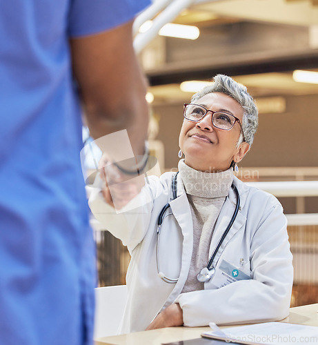 Image of Woman, doctor and handshake with nurse for teamwork, partnership or thank you for healthcare service, meeting or hospital onboarding. Female surgeon shaking hands with nursing staff, trust or support