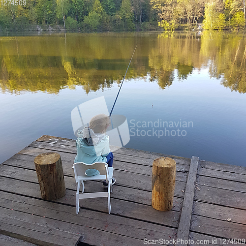 Image of lonely little child fishing from wooden dock on lake