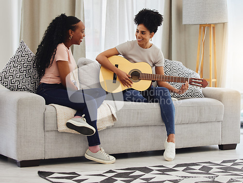 Image of Guitar, happy or women in house for music, social or entertainment while laughing together on sofa. Smile, acoustic or creative musician friends with an instrument for artistic expression in a home