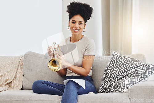 Image of Portrait, woman and trumpet in home for music, learning and practice classic jazz song. Happy young female person, musician and brass horn instrument on sofa, living room and hobby of musical talent