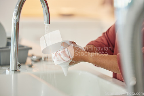 Image of Washing hands, cleaning and person with hygiene and water for wellness in a kitchen faucet. Soap foam, sink and home with bacteria prevention and safety with disinfection with liquid before cooking