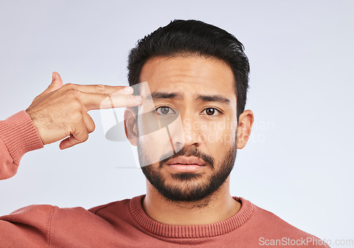 Image of Depression, portrait and sad asian man with hand gun in studio for suicide, trauma or ptsd fail on grey background. Stress, face and guy with weapon emoji for death, anxiety or mental health crisis