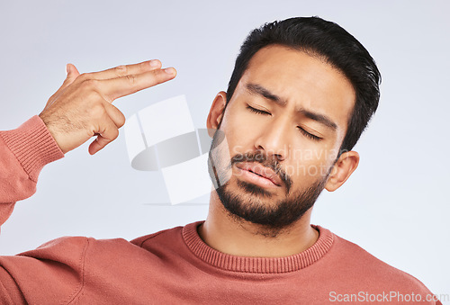 Image of Depression, face and asian man with hand gun in studio for anxiety, trauma or ptsd on grey background. Finger, suicide and male sad with stress, anxiety or self harm, bipolar or mental health crisis