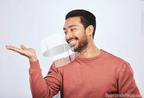 Image of Hand holding, space and happy asian man in studio with mockup, promotion or news on grey background. Smile, face and male person with platform for menu, product placement or sale announcement