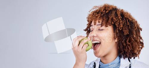 Image of Doctor, woman and eating apple in studio, white background and mockup space. Face of medical employee, happy female nutritionist and bite fruits for vitamin c nutrition, healthy food and vegan diet