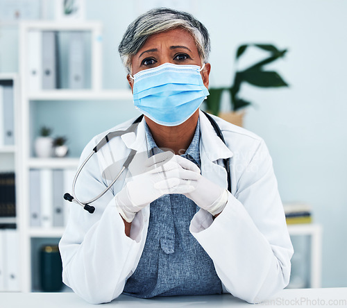 Image of Healthcare, face mask and portrait of a female doctor in her office in the hospital for disease diagnosis. Gloves, concern and professional senior woman medical worker with virus prevention in clinic