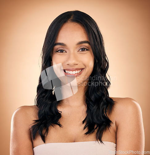 Image of Portrait, hair and salon with a model woman in studio on a brown background for shampoo treatment. Smile, beauty and haircare with a happy young person looking confident about natural cosmetics