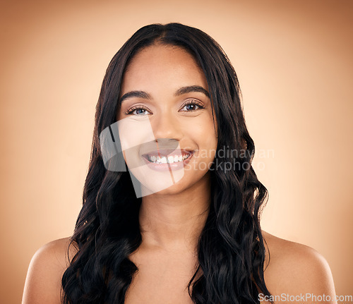 Image of Portrait, hair and smile with a model woman in studio on a brown background for shampoo treatment. Beauty, salon and haircare with a happy young person looking confident about natural cosmetics