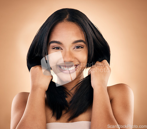 Image of Portrait, hair and skincare with a model woman in studio on a brown background for shampoo treatment. Smile, salon and haircare with a happy young person looking confident about beauty cosmetics