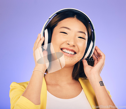 Image of Headphones, music and happy Asian woman in studio listening to audio, streaming song and radio. Entertainment, subscription and female person relax with earphones for album on purple background