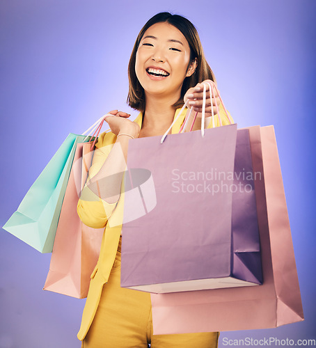 Image of Shopping bag, portrait and woman giving, offer or fashion discount, deal or sale on studio purple background. Giveaway, prize or competition of young customer, model or asian person winning in retail