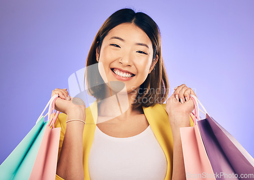 Image of Happy woman, portrait and shopping bag with retail and fashion, commerce and sale on purple background. Discount at boutique shop, Asian female customer and market with store promotion in studio