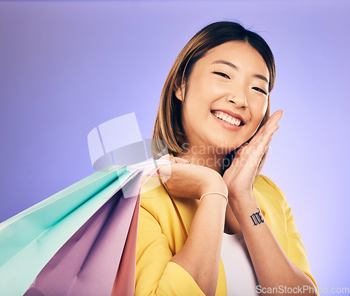 Image of Smile, portrait and woman with shopping bag, retail and commerce with fashion sale on purple background. Discount at boutique shop, Asian female customer and market with store promotion in studio