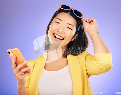 Image of Happy asian woman, portrait and phone in fashion for communication against a purple studio background. Female person or model with smile for networking or stylish clothing on mobile smartphone app