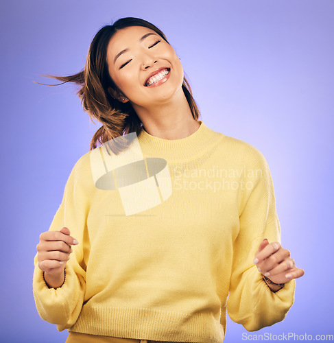 Image of Happy asian woman, dancing and enjoying music, freedom or casual fashion against a purple studio background. Female person or model smile for energy, event or party in happiness for clothing style