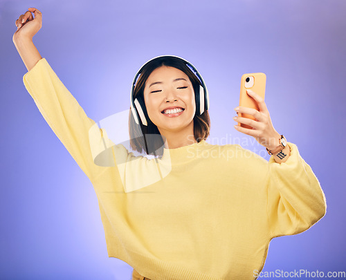 Image of Dance, music and Asian woman with phone in studio for streaming, subscription and radio. Relax, headphones and happy female person on smartphone listen to audio, song and track on purple background