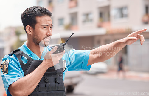 Image of Asian man, police and pointing with walkie talkie in city for emergency dispatch, arrest or calling suspect. Male person, cop or law enforcement with radio signal for communication or safety in town