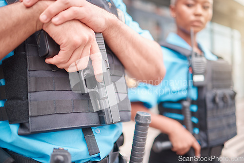 Image of Police, hand and gun with a law enforcement officer standing outdoor in the city while on patrol closeup. Security, safety and protection detail with a guard on the street for crime prevention