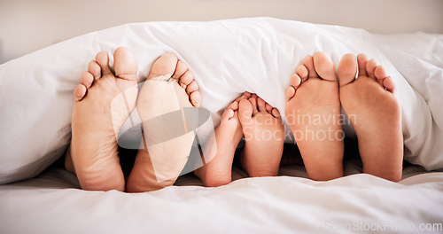Image of Sleeping, feet and family in bed together in the morning, lying in a row to relax in their home. Mom, dad and child dreaming in a bedroom while bonding over the weekend for love, safety or insurance