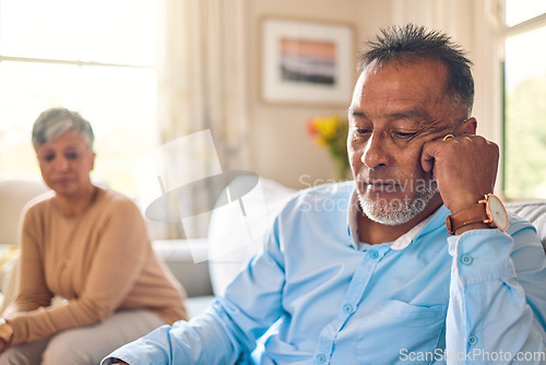 Image of Couple arguing, stress and divorce with a senior man on a sofa in the living room of his home after a fight. Sad, anxiety or depression with an elderly male pensioner looking down after an problem