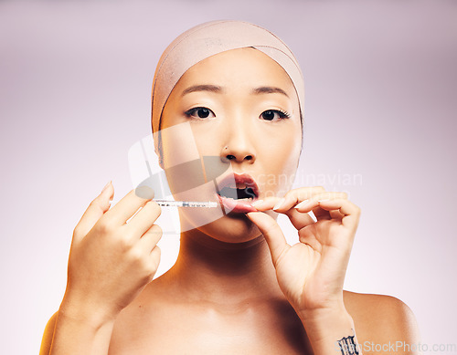 Image of Beauty, lip filler and woman with injection for plastic surgery and portrait of luxury cosmetic dermatology in studio background. Lips, syringe and Asian model with facial treatment for aesthetic