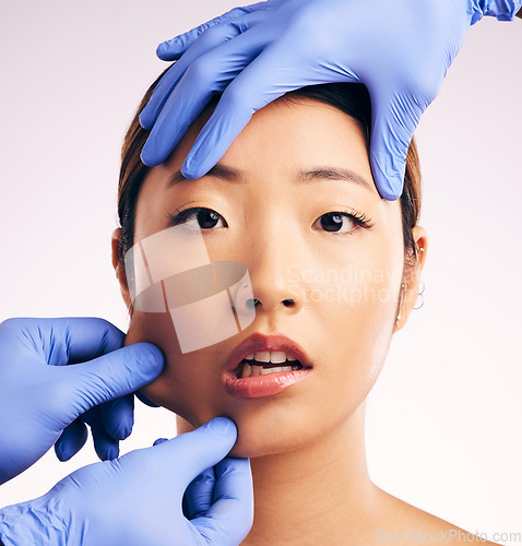 Image of Asian woman, surgery and pinch facial skin in studio for cosmetic, inspection and hands in gloves by white background. Beauty, doctors and check for patient, transformation or shock for pain on face