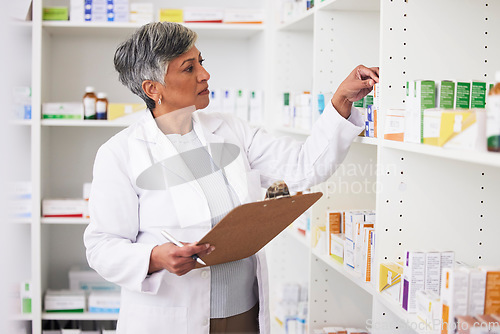 Image of Pharmacy, writing and clipboard of woman with medicine on a shelf for pharmacist inventory. Mature female employee in healthcare, pharmaceutical and medical industry reading information on stock