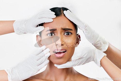 Image of Plastic surgery, scared and face of woman with hands of prp doctors on white background in studio. Beauty, portrait and indian female model with fear, stress and anxiety for facial aesthetic change
