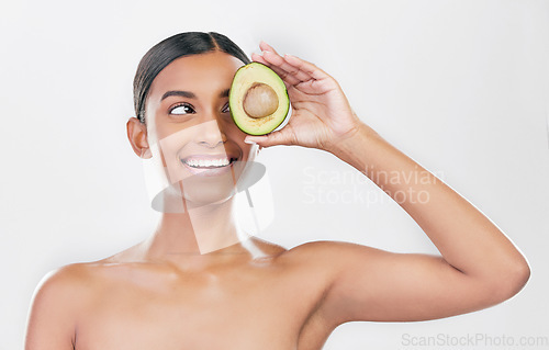 Image of Avocado, eye skincare and happy woman isolated on a white background for healthy facial and cosmetics ideas. Indian person or beauty model thinking of green, vegan or dermatology product in studio