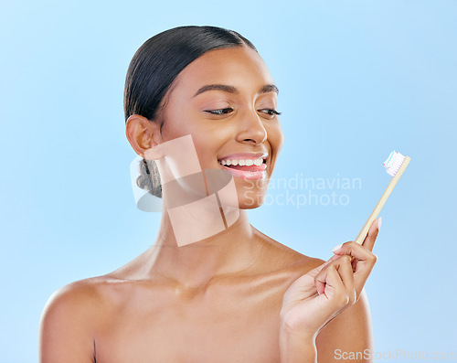 Image of Face, toothbrush and a woman brushing teeth for dental health on a blue background for wellness. Happy indian female model with toothpaste and brush for a clean, fresh and healthy mouth in studio