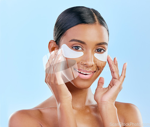 Image of Happy, skincare and portrait of woman with patches for eyes, dark circles and treatment. Smile, face and Indian girl or model with a facial collagen for a glow isolated on a blue background in studio