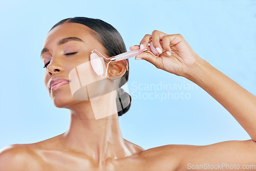 Image of Facial massage, woman and roller, natural beauty and skincare, cosmetics and tools isolated on blue background. Rose quartz, crystal and skin glow, Indian female model with dermatology and antiaging