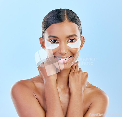 Image of Eye patch, portrait and beauty of a woman with natural skin glow on a blue background. Dermatology, collagen face mask and cosmetics of Indian female model for facial shine and self care in studio