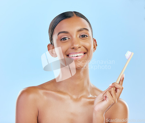 Image of Toothbrush, portrait and a woman brushing teeth for dental health on a blue background for wellness. Happy indian female model with toothpaste and brush for a clean, fresh and healthy mouth in studio