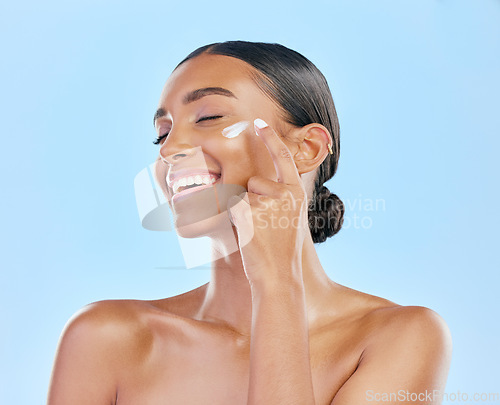 Image of Face cream, skin and beauty of a happy woman with natural glow on a blue background. Dermatology, moisturizer and cosmetics of an Indian female model for facial shine, wellness or self care in studio