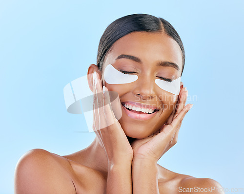 Image of Beauty, eye patch and face of a woman with natural skin glow on a blue background. Dermatology, collagen mask and cosmetics of Indian female model for facial shine and touch for self care in studio