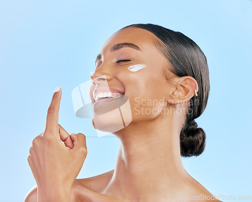 Image of Face cream, skin and beauty of a happy woman with natural glow on a blue background. Dermatology, moisturizer and cosmetics of an Indian female model for facial shine, wellness or self care in studio