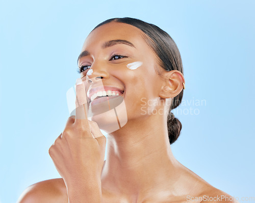 Image of Beauty, face cream and skin of a happy woman with natural glow on a blue background. Dermatology, moisturizer and cosmetics of an Indian female model for facial shine, wellness or self care in studio