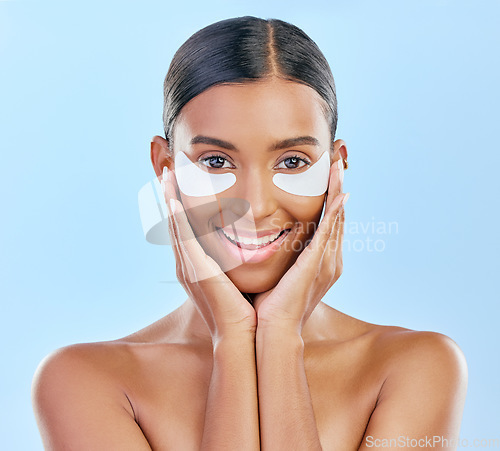Image of Beauty, skincare and portrait of woman with patches for eyes, dark circles and treatment. Smile, spa and Indian girl or model with a facial product for a glow isolated on a blue background in studio