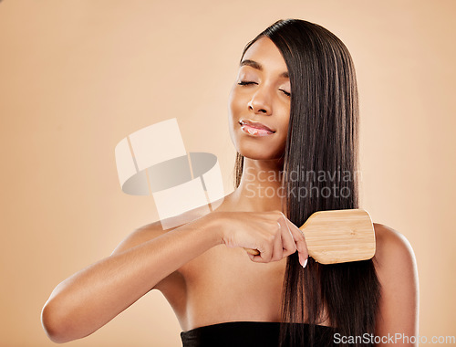 Image of Face, beauty and a woman brushing her hair in studio on a cream background for natural or luxury style. Haircare, growth and shampoo with a young indian female model at the salon or hairdresser