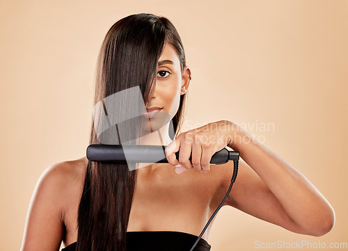 Image of Beauty, flat iron and hair care of a woman in studio with natural glow and shine. Straightener, cosmetics and wellness of Indian person for hairdresser, hot tools or salon results on beige background