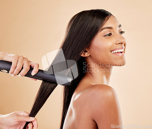 Image of Flat iron, beauty and hair care of a woman in studio with hands of a stylist. Straightener, cosmetics and wellness of Indian person for hairdresser, hot tools or salon results on a beige background