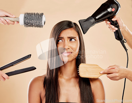 Image of Hair, tools and worry of woman with product for beauty, heat treatment and unhappy on studio background. Indian female model, stress and anxiety for brush, hairdryer and flat iron styling equipment