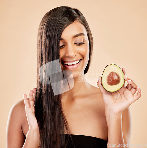 Image of Smile, woman and avocado for hair care, beauty or cosmetic treatment of natural growth on studio background. Happy indian female model, green fruits and vegan dermatology for healthy keratin benefits