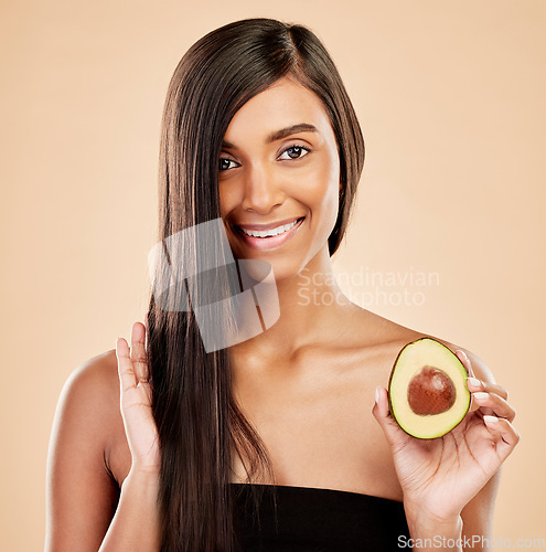 Image of Portrait, woman and avocado for hair, beauty or cosmetic treatment of natural growth on studio background. Happy indian female model, green fruits and vegan dermatology for keratin and aesthetic glow
