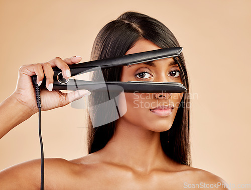 Image of Flat iron, hair and woman with beauty, portrait and hairstyle with appliance isolated on studio background. Keratin treatment, electric straightener and heat, Indian female model with cosmetology