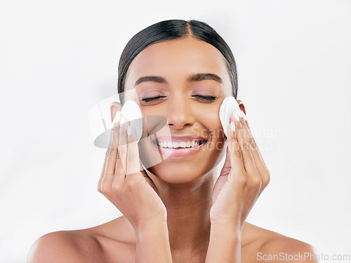 Image of Woman, smile and cotton pad for face, cosmetics and aesthetic skincare in studio on white background. Happy indian female model with beauty products for cleaning, facial dermatology or makeup removal